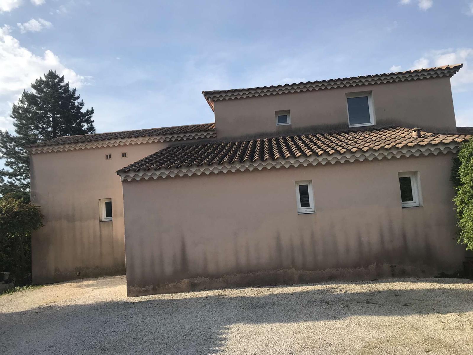 Grande façade de mas provençal noircie par la pollution et les mousses